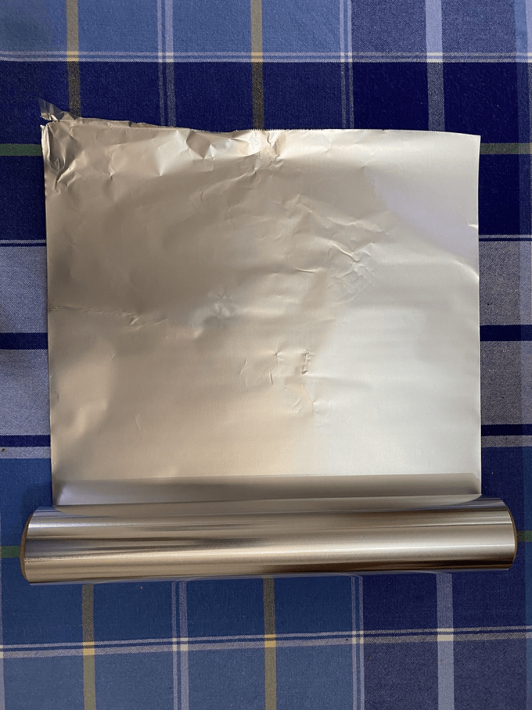 Partially unrolled foil sitting on a patterned tablecloth.